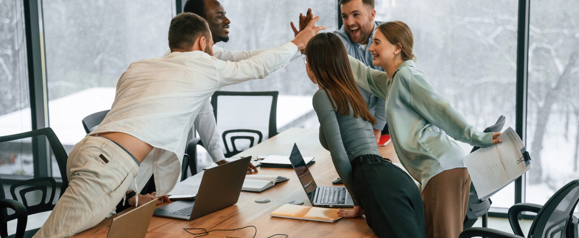 Celebrating success, giving high five. Team of office workers are together indoors.