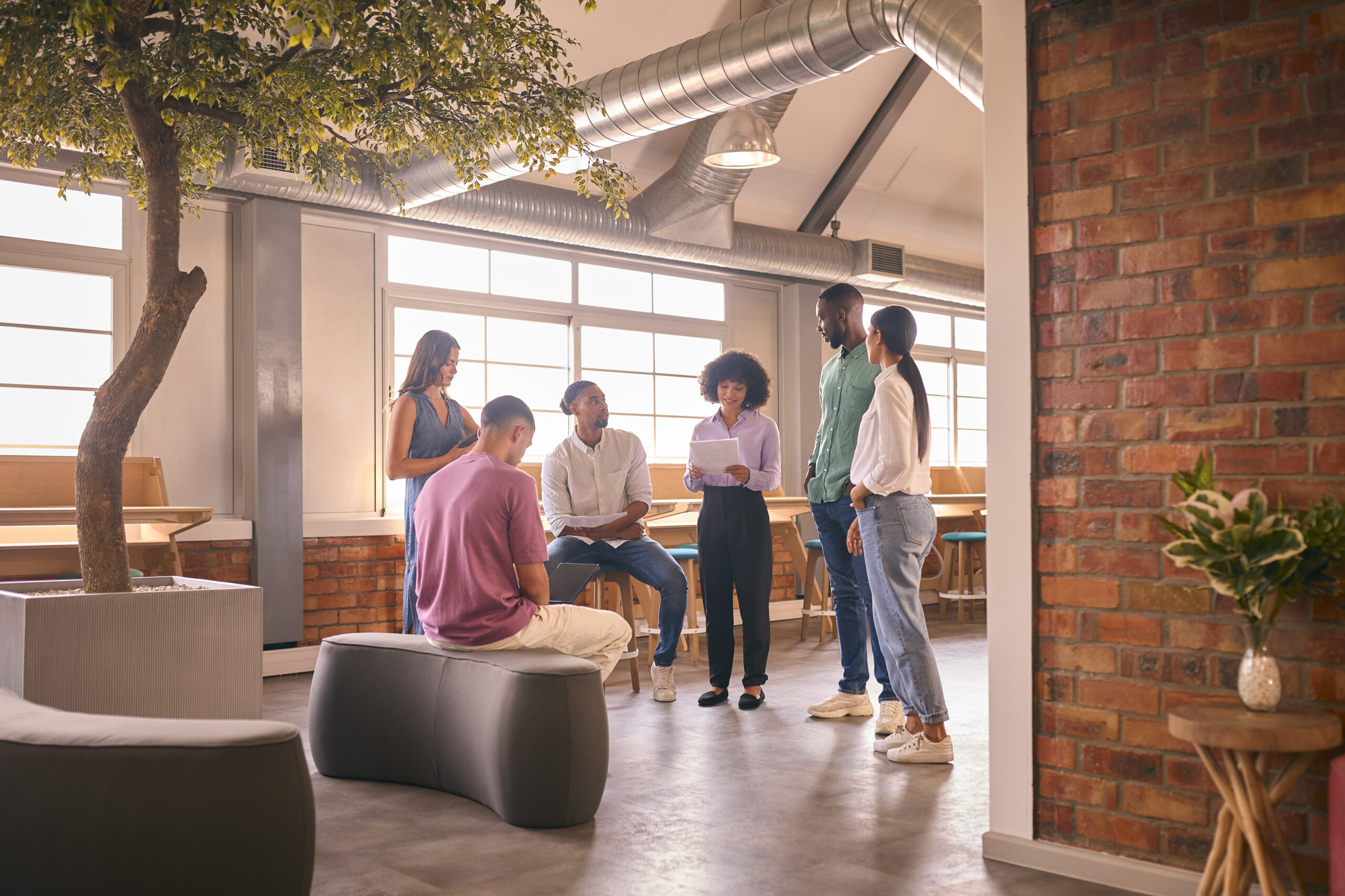 Multi-Cultural Business Team Having Informal Meeting Standing In Modern Open Plan Office Together
