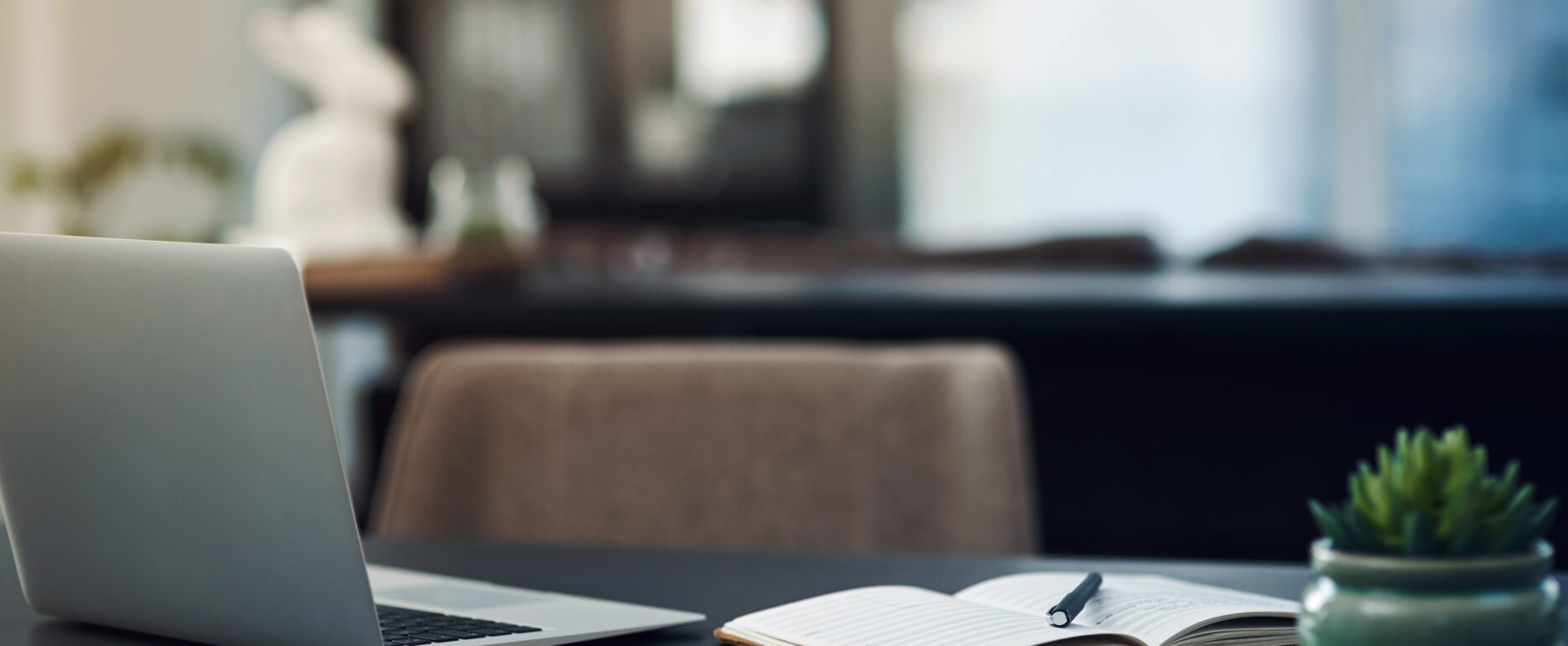 Still life shot of a laptop and notebook on a table in an office.